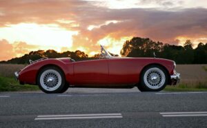 Red convertible parked on roadside at sunset with trees in background in Phoenix AZ